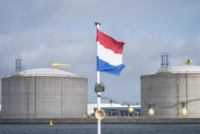 The Dutch national flag flies from a tour boat as liquid natural gas (LNG) silos stand on the shore at the Port of Rotterdam, Netherlands. Photo: Forbes