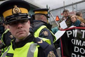 An RCMP officer reads a court order to Federal Green Party Leader Elizabeth May, right, and NDP MP Kennedy Stewart, second right, before they were arrested after joining protesters outside Kinder Morgan's facility in Burnaby, B.C., on Friday March 23, 2018. Photo: Toronto Sun